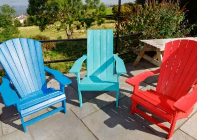 Mixed-colour Adirondack chairs in blue, teal, red and natural on paved patio – Mobek