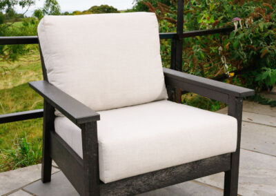 Dark grey recycled plastic deep-seat outdoor armchair with cream cushion on paved patio | Mobek