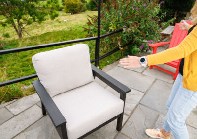 Woman relaxing in grey recycled plastic outdoor armchair with cream cushion on patio | Mobek