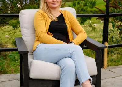 Woman sitting in dark grey recycled plastic outdoor deep-seat armchair with cream cushion | Mobek
