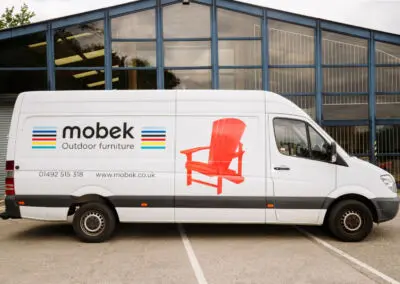 Mobek branded delivery van with red Adirondack chair livery in car park | Mobek