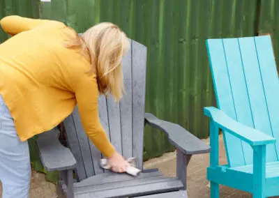 Woman placing teal recycled plastic Adirondack chair outdoors | Mobek