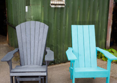 Grey and teal recycled plastic Adirondack chairs on grass outside Mobek warehouse | Mobek