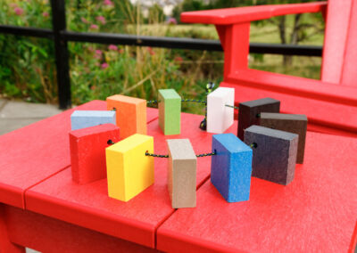 Red Adirondack chair beside red side table displaying colourful recycled plastic colour samples – Mobek