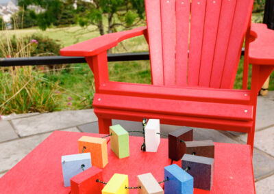 Red Adirondack chairs with colourful recycled plastic side tables on outdoor terrace – Mobek